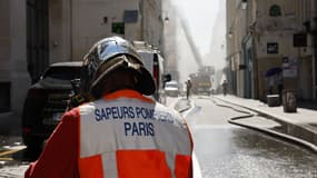 Un pompier parisien travaille sur le site d'un incendie qui a éclaté dans un immeuble à proximité du grand magasin BHV Marais, à Paris, le 25 juin 2024. L'incendie s'est déclaré rue de la Verrerie et le BHV a été évacué.