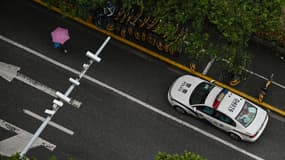 Une voiture des forces de l'ordre patrouille dans le district Jing'an de Shanghai, le 14 avril 2022, en plein confinement dû au Covid-19