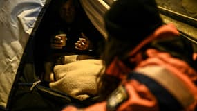 Un bénévole de la protection civile s'adresse à un sans-abri dans une rue à Paris le 9 février 2021 nuit de grand froid