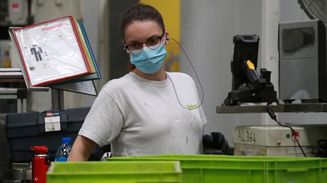 Une salariée de l'usine Valeo travaille avec un masque