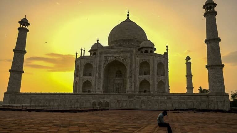 Un gardien du Taj Mahal se repose au lever du soleil le 16 juin 2021, jour de la réouverture de ce monument à Agra en Inde