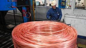Un employé surveille le câble en cuivre de 8 mm de diamètre qui est enroulé avant de passer dans un laminoir pour devenir un câble dans l'usine Nexans de Lens, dans le nord de la France, le 11 mai 2022.
