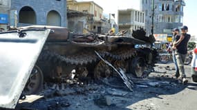 Les combattants druzes syriens marchent près d'un véhicule militaire endommagé, après que les forces gouvernementales syriennes se soient retirées du gouvernorat de Sweida, dans le sud du pays, le 17 juillet 2025.