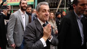 L'ancien président français Nicolas Sarkozy, accompagné de son fils Louis Sarkozy, candidat à la mairie de Menton en 2026, réagit alors qu'il se promène dans les rues de Menton, le 12 décembre 2025, avant une séance de dédicace à la Librairie de la Presse pour la sortie de son livre "Journal d'un prisonnier".