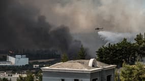 Un hélicoptère lâchant de l'eau au-dessus d'un feu de forêt près d'Acharnes, au nord de la capitale d'Athènes, le 3 août 2021
