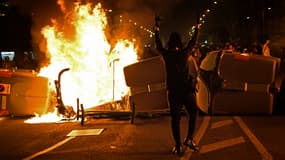 Un manifestant devant des poubelles en feu à Barcelone dans la nuit de jeudi à vendredi.