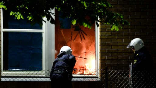 Des policier éteignent un début d'incendie dans une école de Tensta, dans la banlieue de Stockholm, où ont lieu pour la sixième nuit consécutive des émeutes.