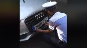 Un policier roumain retirant la plaque insultante de la voiture