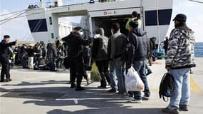 Sur l'île de Lampedusa, des migrants ayant fui la Tunisie sont contrôlés par des policiers avant d'embarquer à bord d'un navire vers d'autres régions de l'Italie.
