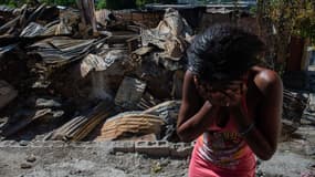 Une femme en larmes devant sa maison après que des bandes armées l’ont incendiée, à Port-au-Prince, le 17 décembre 2024.
