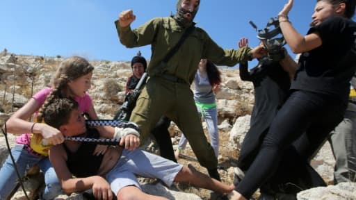 Un soldat israélien plaque un enfant palestinien sur un rocher lors d'affrontements entre les forces de sécurité israéliennes et des manifestants palestiniens, le 28 août 2015 à Nabi Saleh près de Ramallah en Cisjordanie Un soldat israélien plaque un enfant palestinien sur un rocher lors d'affrontements entre les forces de sécurité israéliennes et des manifestants palestiniens, le 28 août 2015 à Nabi Saleh près de Ramallah en Cisjordanie