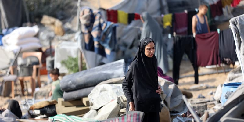 Une femme palestinienne marche parmi des tentes dévastées, après une frappe israélienne nocturne qui a endommagé les abris temporaires, à Gaza, le 13 septembre 2025.