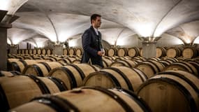 Un ouvrier viticole attend devant des tonneaux de vin dans la "Nouvelle cuverie" pour servir le vin aux personnes qui viennent déguster les vins qui seront vendus lors de la 162e édition de la vente aux enchères de charité des Hospices de Beaune, à Beaune, dans le centre de la France, le 20 novembre 2022.