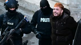 Le trafiquant de drogue français Mohamed Amra (c) escorté par des policiers hors de la Cour d'appel de Bucarest, le 23 février 2025, au lendemain de son arrestation en Roumanie