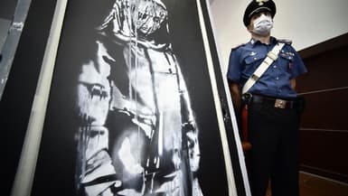 Un policier italien à côté de l'oeuvre de Banksy, volée au Bataclan en 2019, et retrouvée en Italie, lors d'une conférence de presse, le 11 juin 2020 à l'Aquila