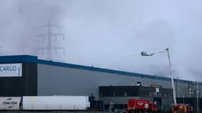 Des pompiers arrosent un bâtiment industriel loué par Bolloré Logistics après avoir lutté toute la nuit contre un incendie, le 17 janvier 2022 à Grand-Couronne, au sud de Rouen.