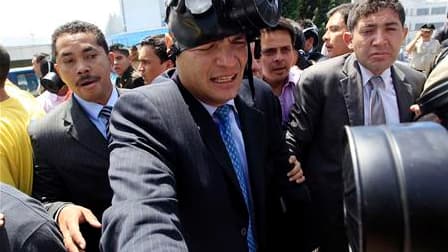 Le président équatorien Rafael Correa s'équipant d'un masque à gaz après avoir été victime de l'explosion d'une grenade lacrymogène alors qu'il tentait de dialoguer avec des policiers manifestant contre des coupes budgétaires, à Quito. Après cette agressi