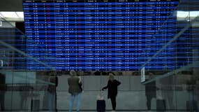 Des voyageurs consultent un tableau d' information sur les vols au départ de l'aéroport Roissy-Charles-de-Gaulle, le 16 septembre 2022
