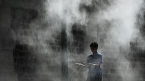 Un jeune garçon profite d'un brumisateur installé sur un quai de la Seine à Paris lors d'une canicule, le 25 juillet 2019
