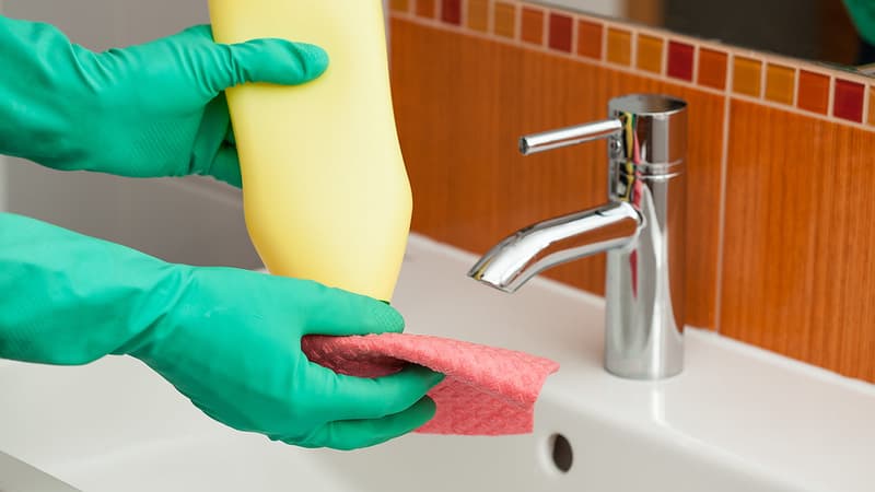 Une personne en train de laver une salle de bain avec du désinfectant (Photo d'illustration)