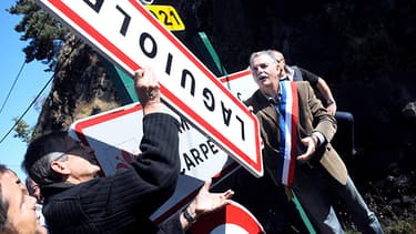 Le maire de Laguiole, Vincent Alazard, retirant le panneau d'entrée de sa commune.