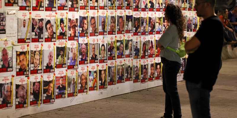 Des personnes regardent des portraits d'otages israéliens, détenus à Gaza depuis l'attaque du 7 octobre, affichés sur un mur à Tel Aviv le 23 avril 2024.