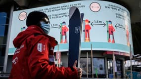 Dans la station de ski de Verbier, en Suisse, un instructeur passe devant un panneau d'instructions sanitaires anti-Covid 19, le 22 décembre 2020