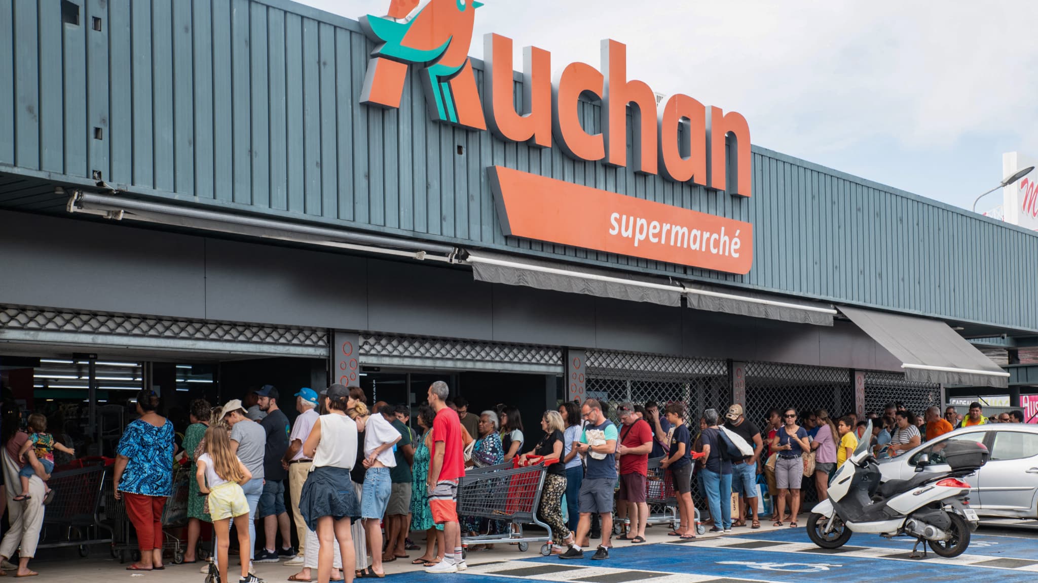 Des habitants font la queue devant un supermarché Auchan de Nouméa le 16 mai 2024