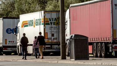 Des migrants marchent à côté de camions stationnés à Calais, le 5 août 2014.