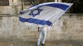 Un colon agite le drapeau d'Israël à Jérusalem dimanche soir. L'Etat hébreux a laissé lundi expirer son moratoire sur la colonisation en Cisjordanie, malgré les appels des Etats-Unis à prolonger cette mesure exigée par les Palestiniens pour poursuivre les