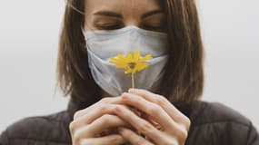 Image d'illustration - personne portant un masque et sentant une fleur