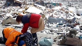 Rescapés du tsunami récupérant des effets personnels dans les ruines de leur maison à Otsuchi. Près d'une semaine après la disparition de leurs maisons emportées par le tsunami, la vie des quelque 1.000 survivants de ce petit port de pêche ne tient toujou