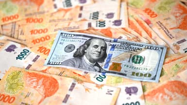 Un billet de 100 dollars américains au-dessus de pesos argentins (photo d'illustration).