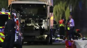 Des agents de police se tiennent près du camion qui a fauché la foule rassemblée sur la Promenade des Anglais, à Nice, le 14 juillet 2016. 