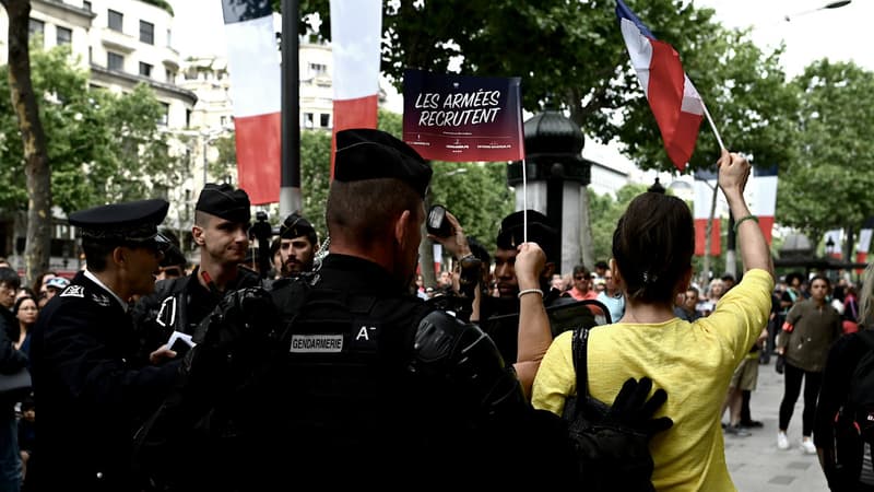 Des gendarmes entourent une femme portant un T-shirt jaune aux abords des Champs-Elysées.