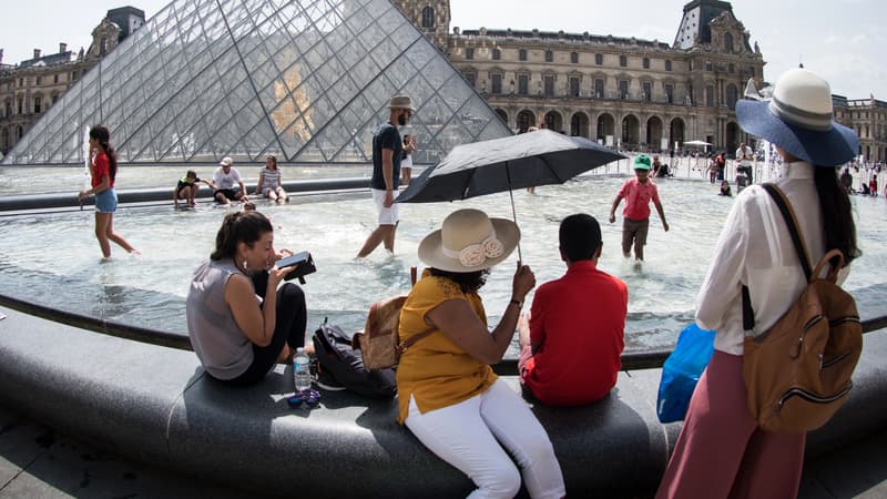 Des touristes en pleine chaleur près de la pyramide du Louvre, à Paris, en août 2018.