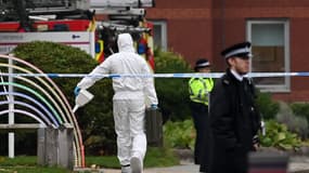 Un spécialiste en combinaison blanche se dirige vers la scène de crime pour examiner la carcasse de la voiture à Liverpool, le 15 novembre. 