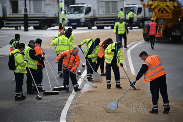 I lavoratori coprono la strada fuori dall'Abbazia di Westminster con la sabbia il 6 maggio 2023.