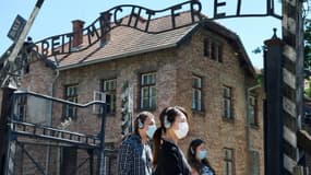 Des visiteurs près de l'entrée du camp nazi d'Auschwitz, le 1er juillet 2020, jour de la réouverture du site après quatre mois de fermeture pour cause de coronavirus