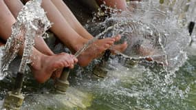 Des touristes se rafraîchissent les pieds dans une fontaine à Montpellier le 2 août, alors que 66 département sont touchés par une vague de canicule.