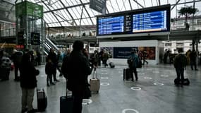Des voyageurs consultent le panneau d'affichage des trains au départ à la Gare de Lyon, au premier jour d'une grève des contrôleurs de la SNCF, le 2 décembre 2022 à Paris.