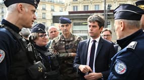 Le Premier ministre Gabriel Attal (R), à côté du gouverneur militaire de Paris et du général du corps d'armée français Christophe Abad (C), s'entretient avec des policiers français lors d'une visite à la gare Saint-Lazare à Paris le 25 mars 2024.