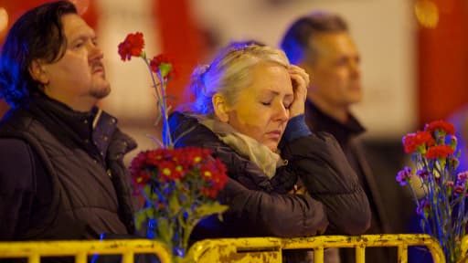 Des gens se recueillent devant les ruines du supermarché, samedi.