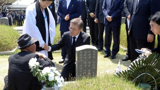 Le nouveau président sud-coréen Moon Jae-In (d) console des familles de victimes devant une tombe du mémorial au cimetière de Gwangju, le 18 mai 2017