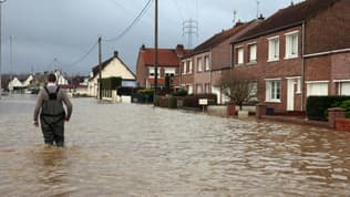 Un homme marche le 3 janvier 2024 dans une rue inondée d'Arques, dans le nord de la France, suite à la crue de l'Aa