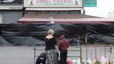 Des passants se recueillent devant la pizzeria où une voiture-bélier a foncé sur la vitrine, tuant une adolescente et blessant grièvement plusieurs personnes.