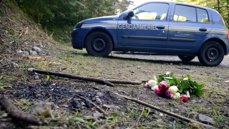 Une voiture de la gendarmerie sur les lieux de la tuerie où une gerbe a été déposée.