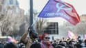 Des partisans de la France Insoumise agitent un drapeau du mouvement le 6 mars 2022 lors d'un meeting de Jean-Luc Mélenchon