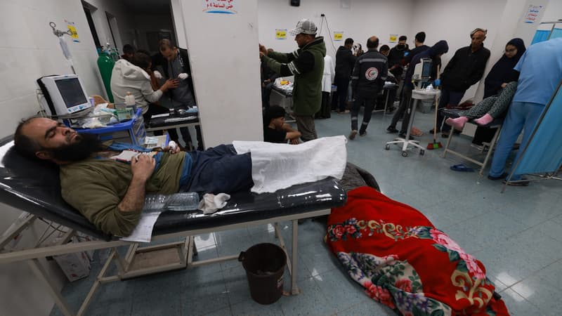 Un homme blessé attend d'être soigné alors qu'un cadavre se trouve au sol, à l'hôpital koweïtien de Rafah, après des bombardements israéliens, le 12 février 2024.