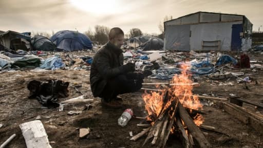 Hemn, un migrant kurde, se réchauffe près d'un feu, le 18 janvier 2016 dans le camp de la "Jungle", à Calais, dans le nord de la France Hemn, un migrant kurde, se réchauffe près d'un feu, le 18 janvier 2016 dans le camp de la "Jungle", à Calais, dans le nord de la France